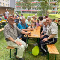 Bild mit Nachbarn der Florian-Geyer-Straße, die an Biertischgarnituren und sich unterhalten