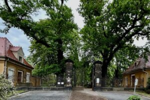 Eingangstor Trinitatisfriedhof, im Hintergrund große, alte Bäume