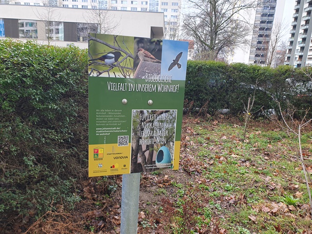 Schilder weisen auf die biologische Vielfalt im Wohnhof hin.