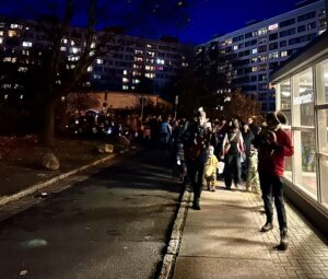 Erwachsene und Kinder mit Laternen folgen einem Tubaspieler im Dunkeln