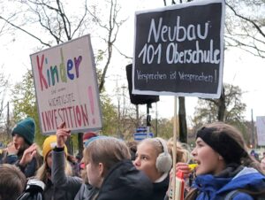 Menschen halten Schilder bei einer Demonstration hoch.