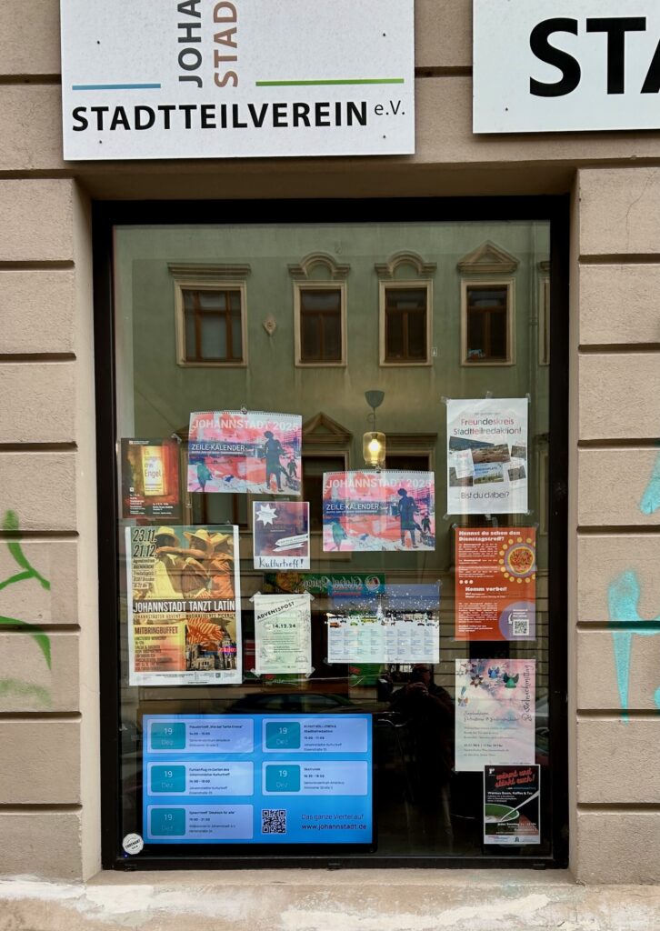 Schaufenster mit Plakaten und einem Bildschirm.