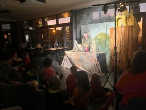 Kinder schauen ein Puppentheater an.